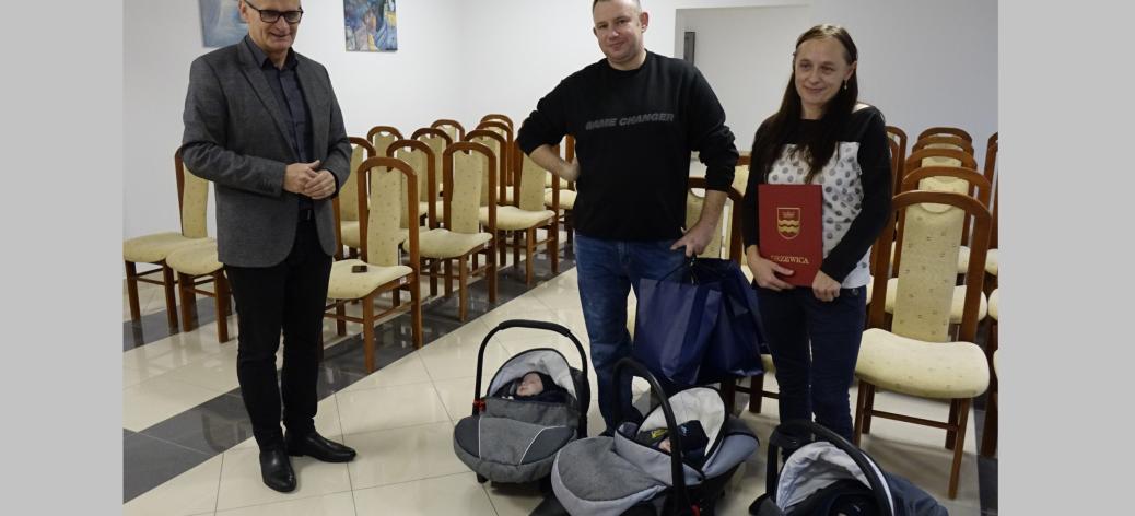 Burmistrz Drzewicy Janusz Reszelewski i rodzice trojaczków z chłopcami leżącymi w nosidełkach