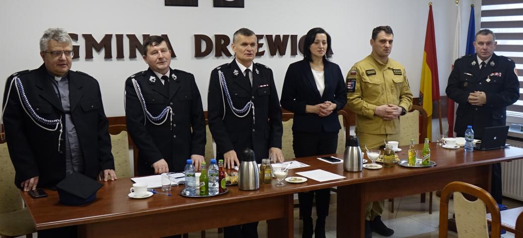 Za stołem prezydialnym stoją gminne władze ZOSP RP w Drzewicy i goście zebrania