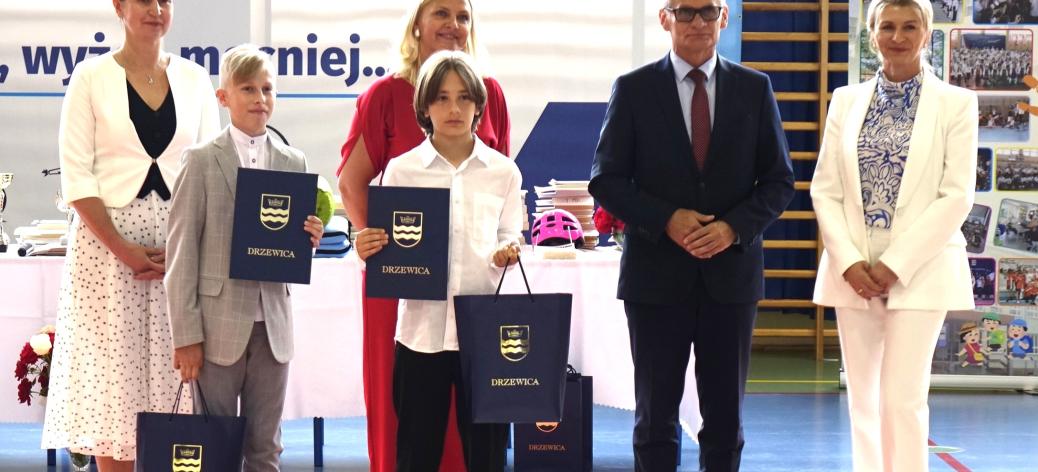 Wspólne zdjęcie najlepszych uczniów w Gminie Drzewica - Marcela Wrzoska i Bartłomieja Kupisa - wraz z Burmistrzem Drzewicy Januszem Reszelewskim, Dyrektor ZEAS Agnieszką Kwiecień, Dyrektor SP w Drzewicy Agnieszką Bogatek i Wicedyrektor SP w Drzewicy Justyną Bombą.