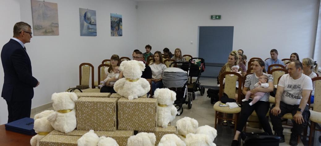 Widok ogólny na salę USC. Rodzice z bobasami siedzą na krzesłach. Przed nimi głos zabiera Burmistrz Drzewicy Janusz Reszelewski.