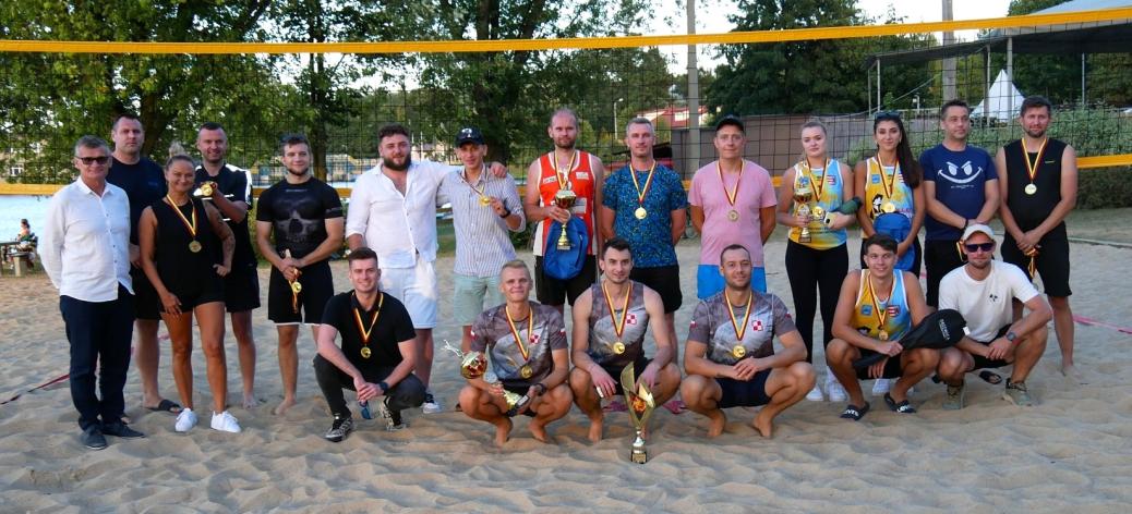 Grupowe zdjęcie uczestników i organizatorów turnieju na piaszczystym boisku pod siatką