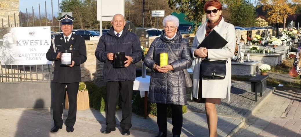 zworo społeczników TPD – dwie panie i dwóch panów – stoi z puszkami kwestarskimi obok wejścia na głównej alei cmentarza parafialnego w Drzewicy
