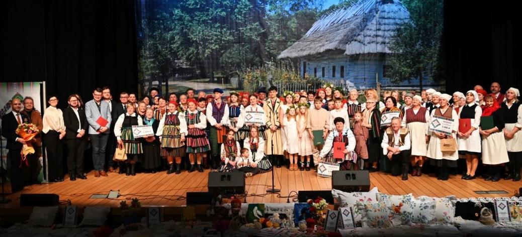 Pamiątkowe zdjęcie stojących na scenie uczestników i organizatorów Rewii Sztuki Ludowej