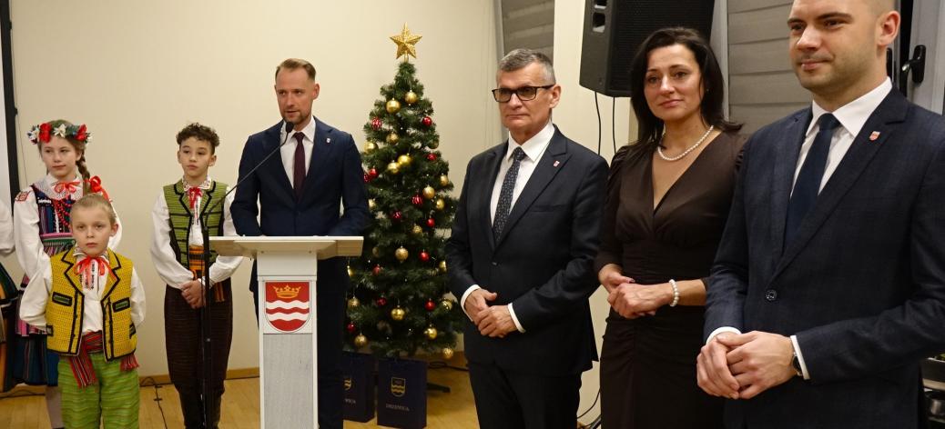 W sali konferencyjnej RCK stoją od lewej: troje „Małych Drzewiczan”, konferansjer Piotr Bajerowski z Urzędu Miejskiego w Drzewicy, Burmistrz Janusz Reszelewski, Przewodnicząca Rady Miejskiej w Drzewicy Dorota Wiktorowicz i Zastępca Burmistrza Dominik Niemirski. 