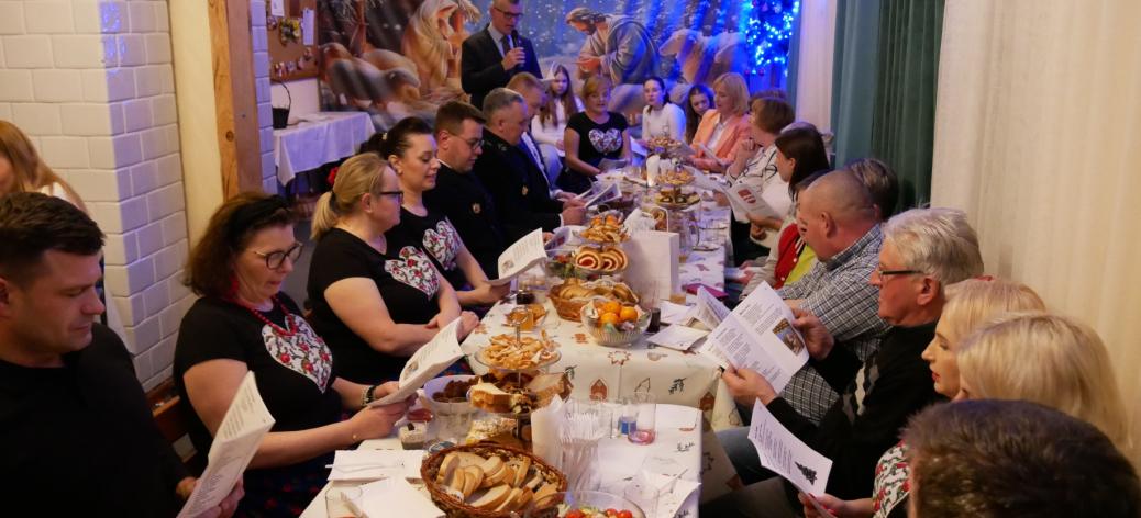 Przy zastawionym stole w siedzibie KGW w Radzicach Małych kolędują Burmistrz Janusz Reszelewski wraz z mieszkańcami sołectwa. 