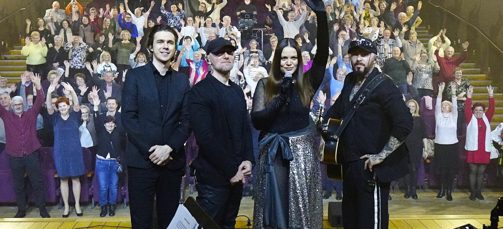 Zespół Blue Cafe w czteroosobowym składzie stoi na scenie odwrócony tyłem do wiwatującej widowni. 