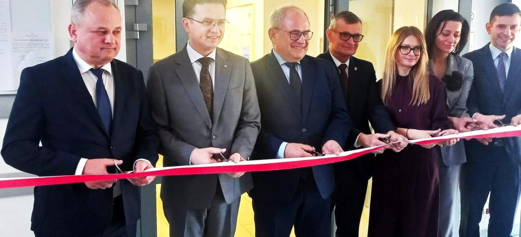 Symbolicznego przecięcia wstęgi dokonuje siedem osób - od lewej: Członek Zarządu Województwa Łódzkiego Artur Ostrowski, II Wicewojewoda Łódzki Grzegorz Majewski, I Wicewojewoda Łódzki Marek Mazur, Burmistrz Drzewicy Janusz Reszelewski, p.o. Zastępcy Dyrektora Wojewódzkiego Urzędu Pracy w Łodzi Aneta Dziemdziela, Przewodnicząca Rady Miejskiej w Drzewicy Dorota Wiktorowicz oraz p.o. Zastępcy Dyrektora Regionalnego Centrum Polityki Społecznej w Łodzi Oskar Kuliński.