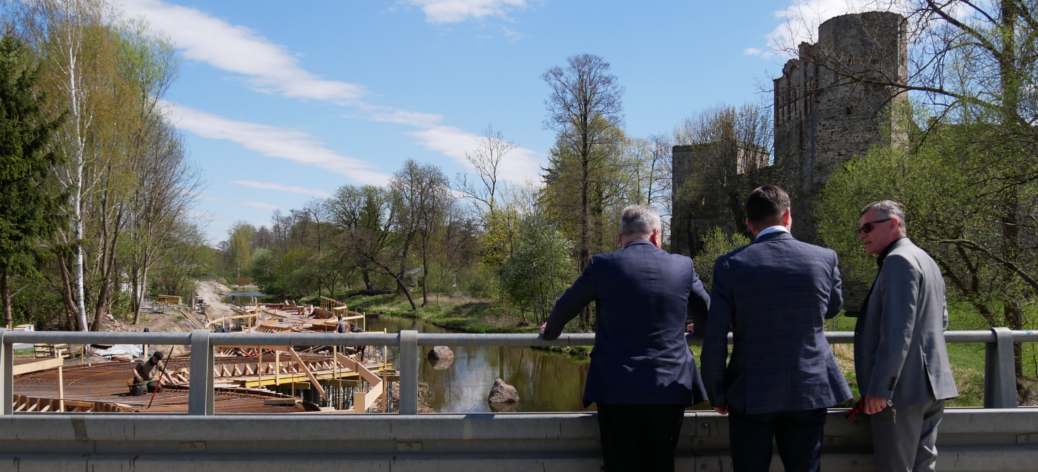 Na moście w Drzewicy stoją Marszałek Województwa Łódzkiego, Zastępca Dyrektora RCPS w Łodzi oraz Burmistrz Drzewicy, w tle budowa bulwaru, rzeka Drzewiczka oraz biskupi zamek w Drzewicy