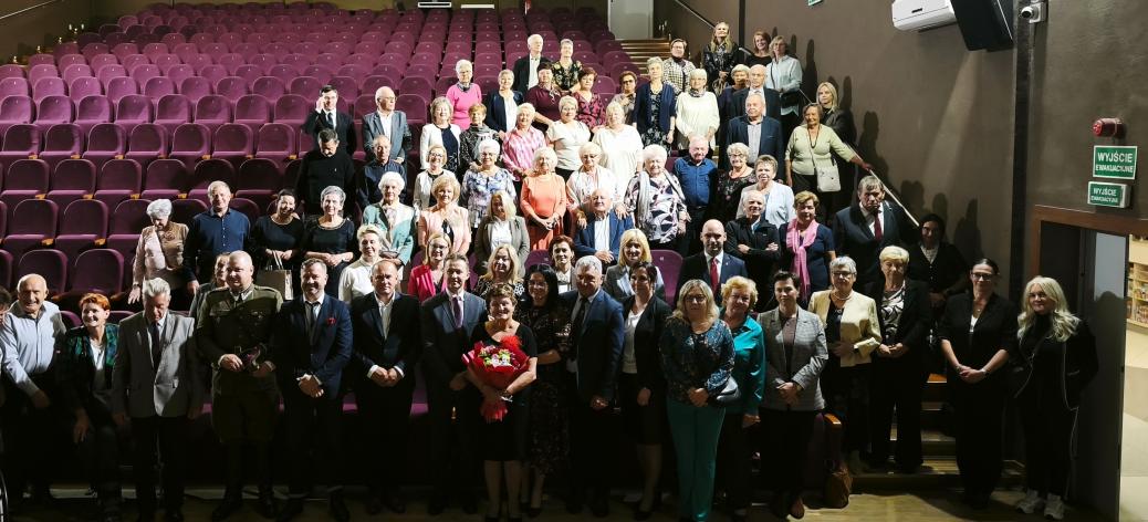 Pamiątkowe zdjęcie grupowe wszystkich uczestników wydarzenia stojących na widowni w sali widowiskowej RCK.