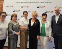 Przed ścianką promocyjną Urzędu Marszałkowskiego Województwa Łódzkiego stoją od lewej: Przewodnicząca Miejskiej Rady Seniorów w Drzewicy Barbara Oliwa, radna senioralna Zdzisława Majchrowska, Wojewoda Łódzki Dorota Ryl, radna senioralna Jadwiga Szcześniak, Pełnomocnik Wojewody Łódzkiego do spraw polityki senioralnej Jolanta Chełmińska, Zastępca Burmistrza Drzewicy Dominik Niemirski