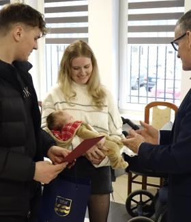 Burmistrz Drzewicy Janusz Reszelewski przekazuje gratulacje rodzicom trzymającym małe dziecko
