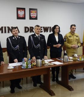 Za stołem prezydialnym stoją gminne władze ZOSP RP w Drzewicy i goście zebrania