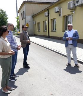 Uczestnicy odbioru (sześć osób) stoją na przebudowanej drodze przy budynku byłego dworca PKP w Drzewicy