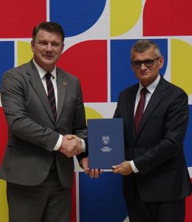 Na tle ścianki promocyjnej Województwa Łódzkiego w uścisku dłoni Członek Zarządu Województwa Łódzkiego Artur Bagieński oraz Burmistrz Drzewicy Janusz Reszelewski
