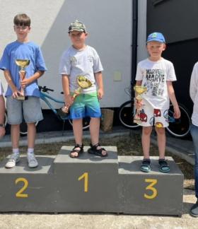 Dekoracja w kategorii chłopców. Na podium trzej młodzi wędkarze z pucharami. Obok po lewej Prezes Koła nr 3 PZW w Drzewicy Ziemowit Jaciubek, po prawej Burmistrz Drzewicy Janusz Reszelewski