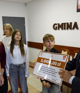 Delegacja SP w Idzikowicach – nauczyciel i troje uczniów – odbiera plastikową promesę od Burmistrza Drzewicy Janusza Reszelewskiego (pierwszy z prawej). Z tyłu Dyrektor ZEAS Małgorzata Kuchenbecker.