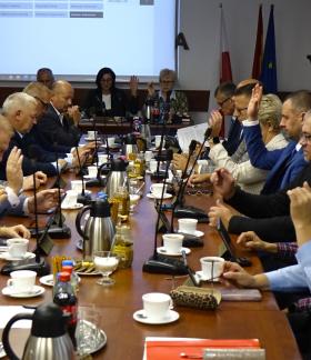 Uczestnicy sesji siedzą przy stołach w sali konferencyjnej Urzędu Miejskiego w Drzewicy. Radni biorą udział w głosowaniu