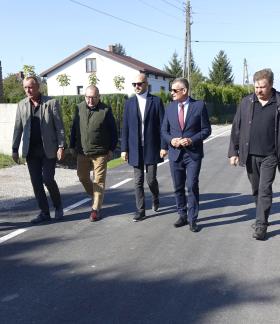 Wyremontowaną drogą w Brzustowcu – Starej Wsi idą uczestnicy odbioru – siedmiu mężczyzn.