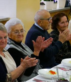 Pięcioro emerytowanych nauczycieli siedzi przy stole. Pięć osób klaszcze.