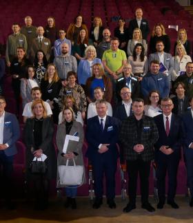 Wspólne zdjęcie uczestników spotkania stojących w rzędach na widowni sali kinowo-widowiskowej RCK