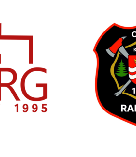 Na zdjęciu dwa logotypy: od lewej logotyp Krajowego Systemu Ratowniczo Gaśniczego – składający się z napisu KSRG, roku 1995 oraz paru linii w kolorze czerwonym na kształt tarczy i terytorium administracyjnego Rzeczpospolitej Polskiej; logotyp OSP Radzice – na czarnej tarczy z czerwoną obwódką znajdują się napisy OSP, 1926 oraz Radzice, a także topór skrzyżowany z siekierą a przed nimi Herb Gminy Drzewica. 