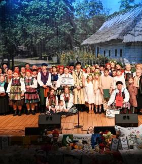 Pamiątkowe zdjęcie stojących na scenie uczestników i organizatorów Rewii Sztuki Ludowej