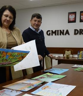 W sali konferencyjnej UM w Drzewicy dwie nauczycielki i Gminny Komendant ZOSP RP oceniają prace plastyczne. Po prawej stronie na ścianie napis Gmina Drzewica, godło Polski i herb Drzewicy