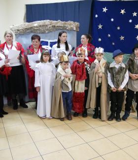 Czternastoosobowa grupa dzieci i dorosłych prezentująca przedstawienie jasełkowe