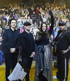 Zespół Blue Cafe w czteroosobowym składzie stoi na scenie odwrócony tyłem do wiwatującej widowni. 