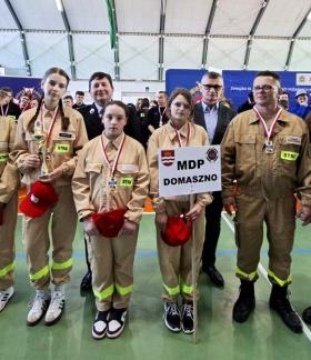 W hali sportowej stoi pięcioosobowa drużyna dziewcząt z OSP Domaszno wraz z opiekunem, Gminnym Komendantem ZOSP w Drzewicy, Burmistrzem Drzewicy i Prezesem Oddziału Powiatowego ZOSP RP w Opocznie.  Dziewczęta mają medale i puchar.