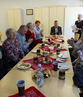  Przy stole siedzi kilkanaście osób - niewidomi i niedowidzący z opiekunami, Dyrektor RCK Alina Szymańska oraz Burmistrz Drzewicy Janusz Reszelewski. Stoi Pani Aleksandra Domańska