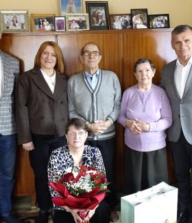 W pokoju na tle meblościanki stoi pięć osób oraz jedna siedzi z przodu. W centrum stoją Szanowni Jubilaci. Po ich bokach znajdują się trzy osoby dorosłe, w tym po prawej Burmistrz Drzewicy. Na pierwszym planie siedzi kobieta trzymająca bukiet czerwono-białych kwiatów. 