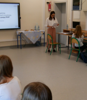 Zdjęcie przedstawia uczestników posiedzenia Młodzieżowej Rady Miejskiej w Drzewicy, którzy siedzą przy stolikach z laptopami w sali komputerowej