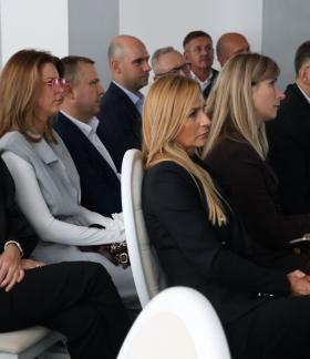 Uczestnicy spotkania biznesowego siedzą na krzesłach i słuchają prezentacji.