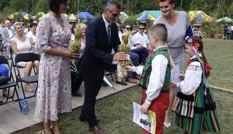 Przewodnicząca Rady Miejskiej w Drzewicy Dorota Wiktorowicz i Burmistrz Drzewicy Janusz Reszelewski odbierają od dzieci bukiet zbóż. Obok Dyrektor RCK w Drzewicy Alina Szymańska
