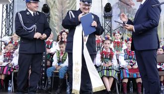  Kapelan Strażaków Gminy Drzewica ks. Jarosław Wypchło odbiera list gratulacyjny i stułę. Po lewej Gminny Komendant ZOSP RP w Drzewicy Marian Kalużny, po prawej Burmistrz Drzewicy Janusz Reszelewski