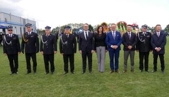 Zaproszeni goście oraz przedstawiciele władz i druhowie OSP Radzice  - 10 osób - pozują na płycie boiska po dekoracji odznaką „Wzorowy Strażak”