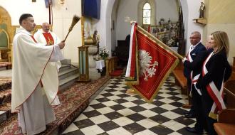 Ks. kan. Adam Płuciennik dokonuje poświęcenia sztandaru szkoły podczas mszy świętej w kościele pw. św. Łukasza w Drzewicy. Obok drzewickiego proboszcza ks. Ireneusz Wiktorowicz. Po prawej stronie trzyosobowy poczet sztandarowy składający się z potomków Jana Szymańskiego