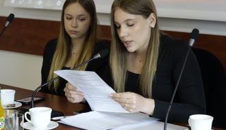Prezydium Młodzieżowej Rady Miejskiej w Drzewicy. Przy stole prezydialnym siedzą: po prawej Przewodnicząca Rady Nikola Najman (odczytuje porządek obrad), po lewej Wiceprzewodnicząca Rady Karolina Białek