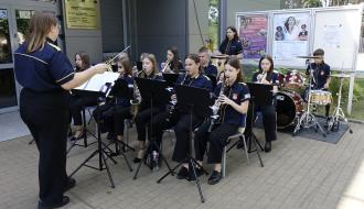 Kilkunastoosobowy skład Młodzieżowej Orkiestry Dętej z Regionalnego Centrum Kultury daje powitalny koncert przed wejściem do budynku RCK