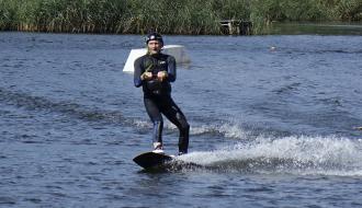 Na desce do wakeboardingu po tafli jeziora płynie Karol Żarski