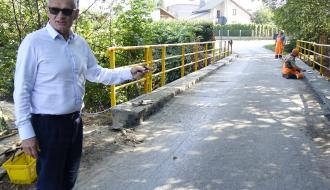 Burmistrz Drzewicy Janusz Reszelewski stoi przed mostem w Giełzowie, wskazując ręką na miejsce trwających robót