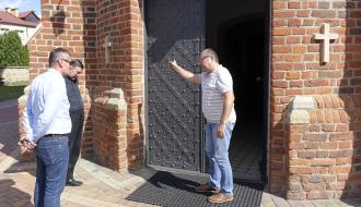 Przed głównymi drzwiami do drzewickiego kościoła stoją: Burmistrz Drzewicy Janusz Reszelewski, Proboszcz Parafii w Drzewicy ks. kan. Adam Płuciennik oraz Jarosław Bomba – Kierownik Referatu Gospodarki Komunalnej, Budownictwa i Inwestycji Urzędu Miejskiego w Drzewicy