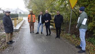 Uczestnicy odbioru  - sześć osób – stoją na drodze przed wyremontowanym mostem w Giełzowie