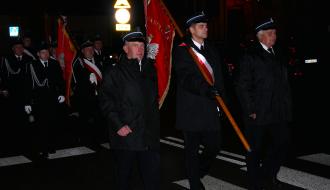 Wieczorny przemarsz do kościoła pw. św. Łukasza. Na przedzie trzyosobowy poczet sztandarowy OSP Drzewica