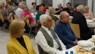 Ponad dwadzieścia osób uczestniczących w uroczystości siedzi przy stołach w sali stowarzyszeń RCK