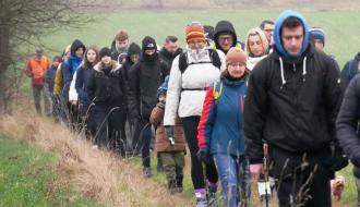 Kilkudziesięcioosobowa grupa piechurów idzie drogą gruntową między polami na Dąbrówce.