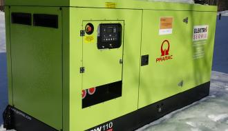 Agregat prądotwórczy o mocy 80 kW w kolorze jasnej zieleni, stojący na zewnątrz w zimowej scenerii