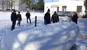 Uczestnicy odbioru oglądają gazowy zbiornik naziemny usytuowany na zaśnieżonym placu obok świetlicy