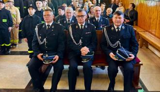 Wnętrze kościoła w Domasznie wypełnione uczestnikami uroczystej mszy świętej. Na przedzie trzej strażacy w galowych mundurach siedzący w pierwszej ławce, z grupą młodszych strażaków i wiernych w tle.